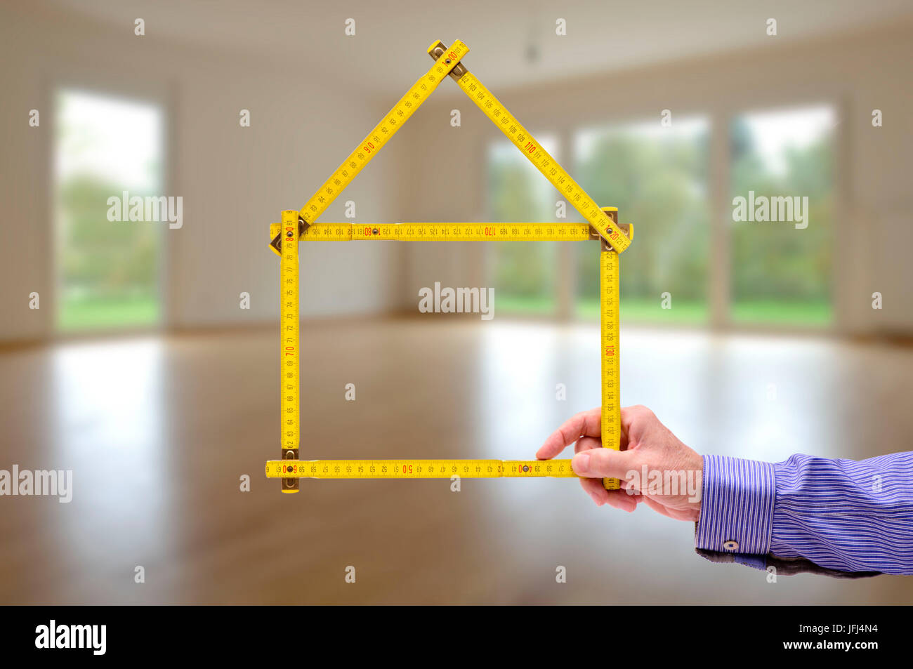 Bastone cantiere simbolicamente come un modello di casa in salotto Foto Stock