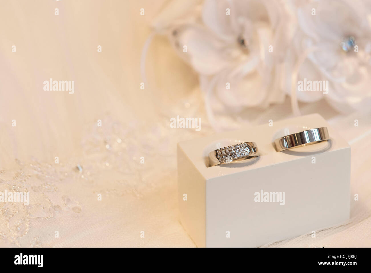 Gli anelli di nozze in oro e platino con diamanti su uno sfondo costituito di lacy Foto Stock