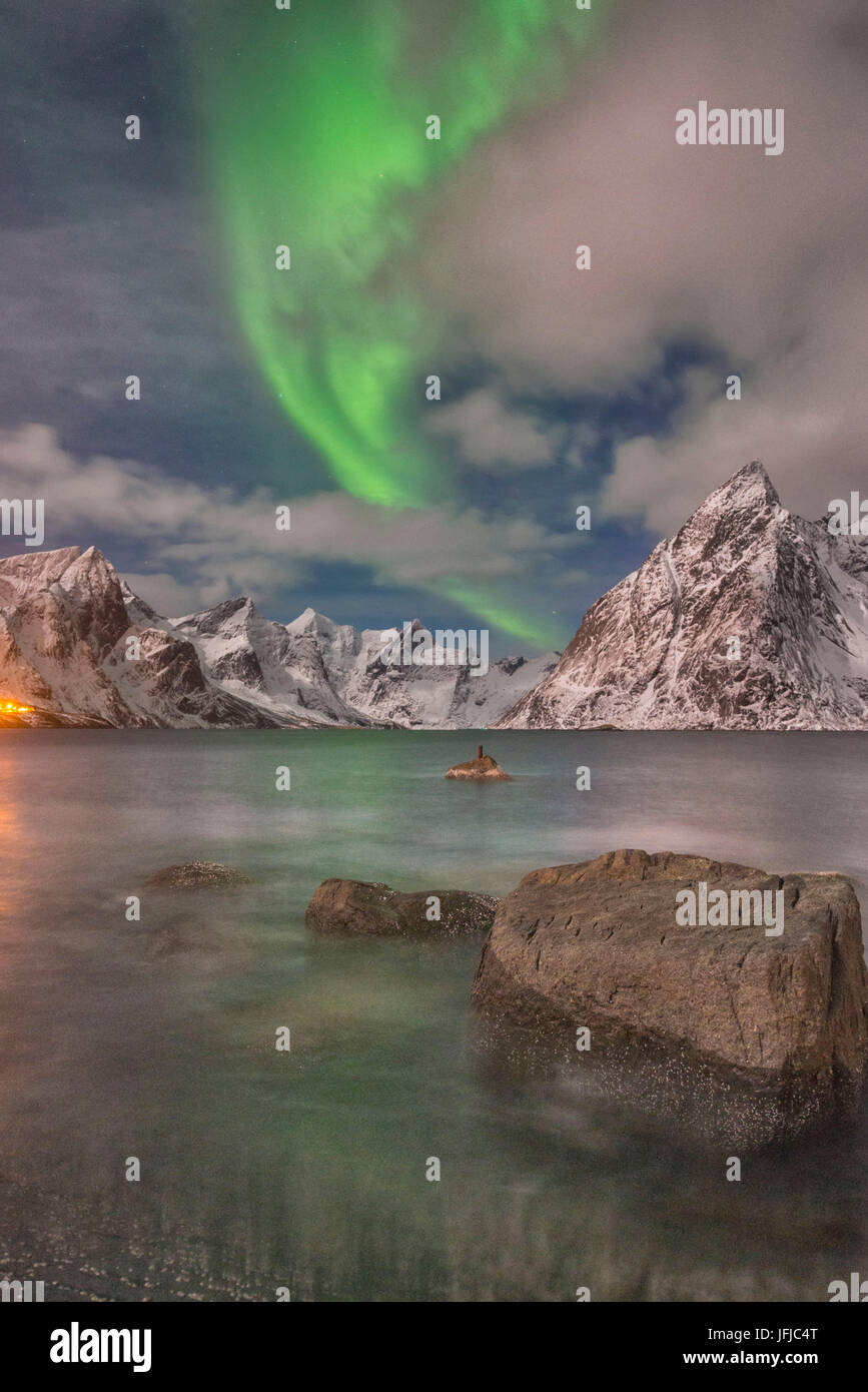 Piccola aurora con le nuvole, rocce vicino all'oceano, le piccole città e le montagne sul retro, Hamnoy Isola, Lofoten, Norvegia Foto Stock