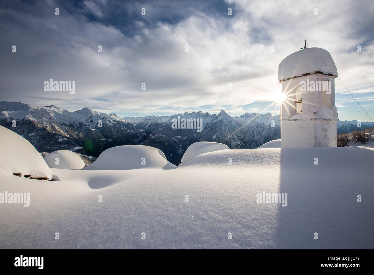 Inverno il sole splende dietro il pittoresco campanile presso l'Alpe Scima dopo una nevicata, Valchiavenna, Valtellina Lombardia Italia Europa Foto Stock