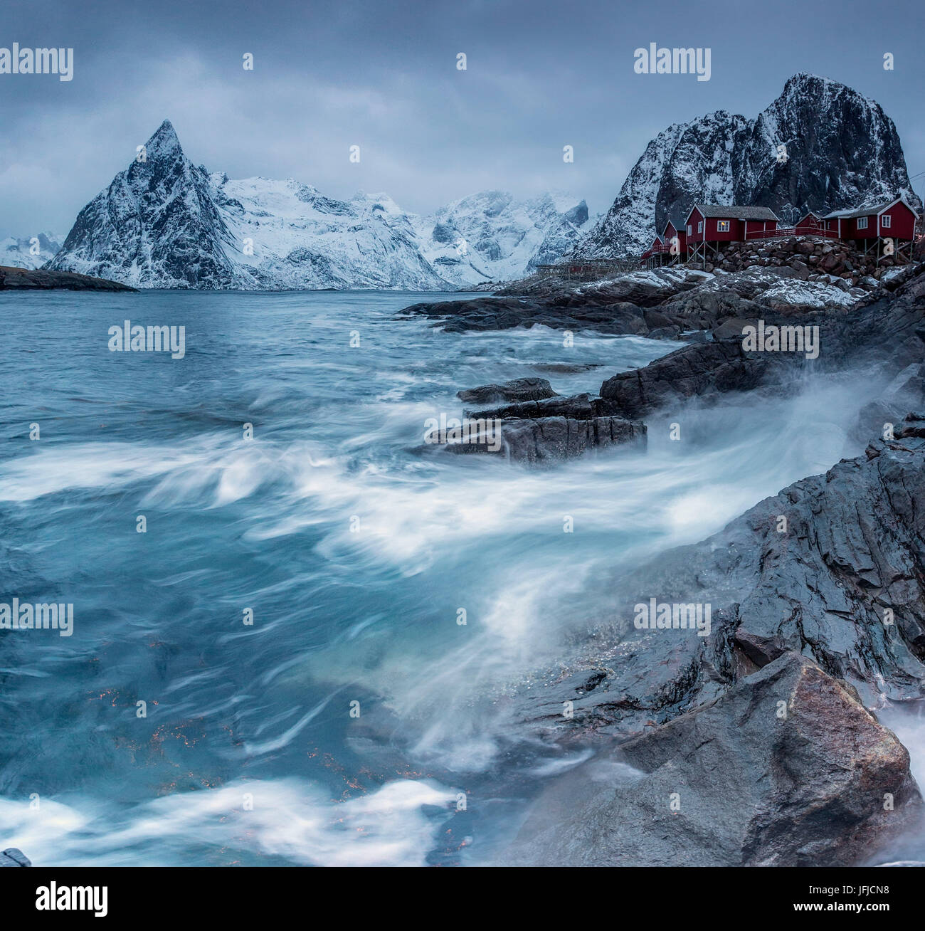 Onde che si infrangono sulle rocce vicino alle case dei pescatori, Hamnøy, Isole Lofoten Norvegia del Nord Europa Foto Stock