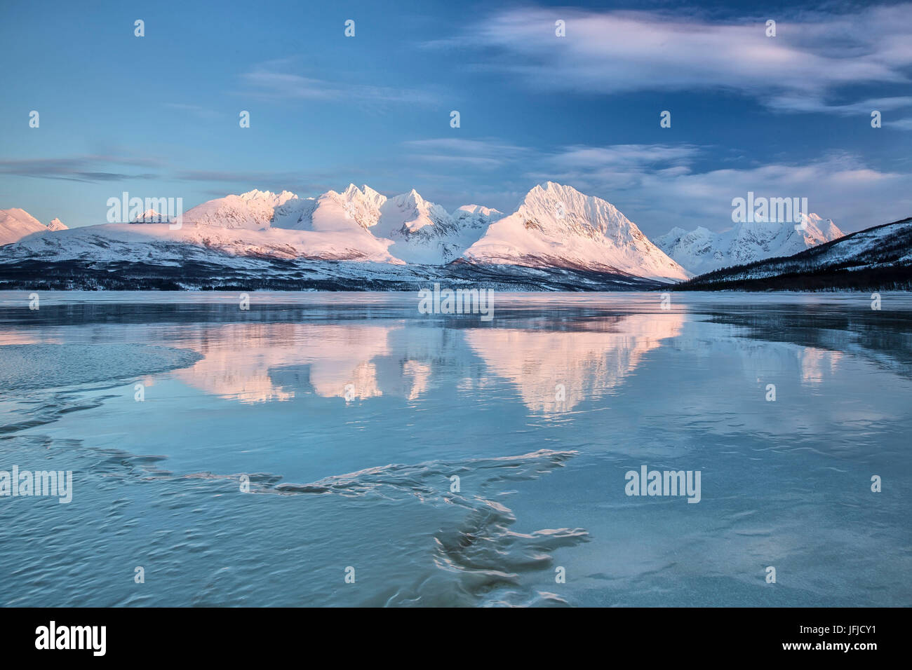 Cielo blu e vette innevate sono riflesse nel lago ghiacciato Jaegervatnet Stortind Alpi Lyngen Tromsø Lapponia Norvegia Europa Foto Stock