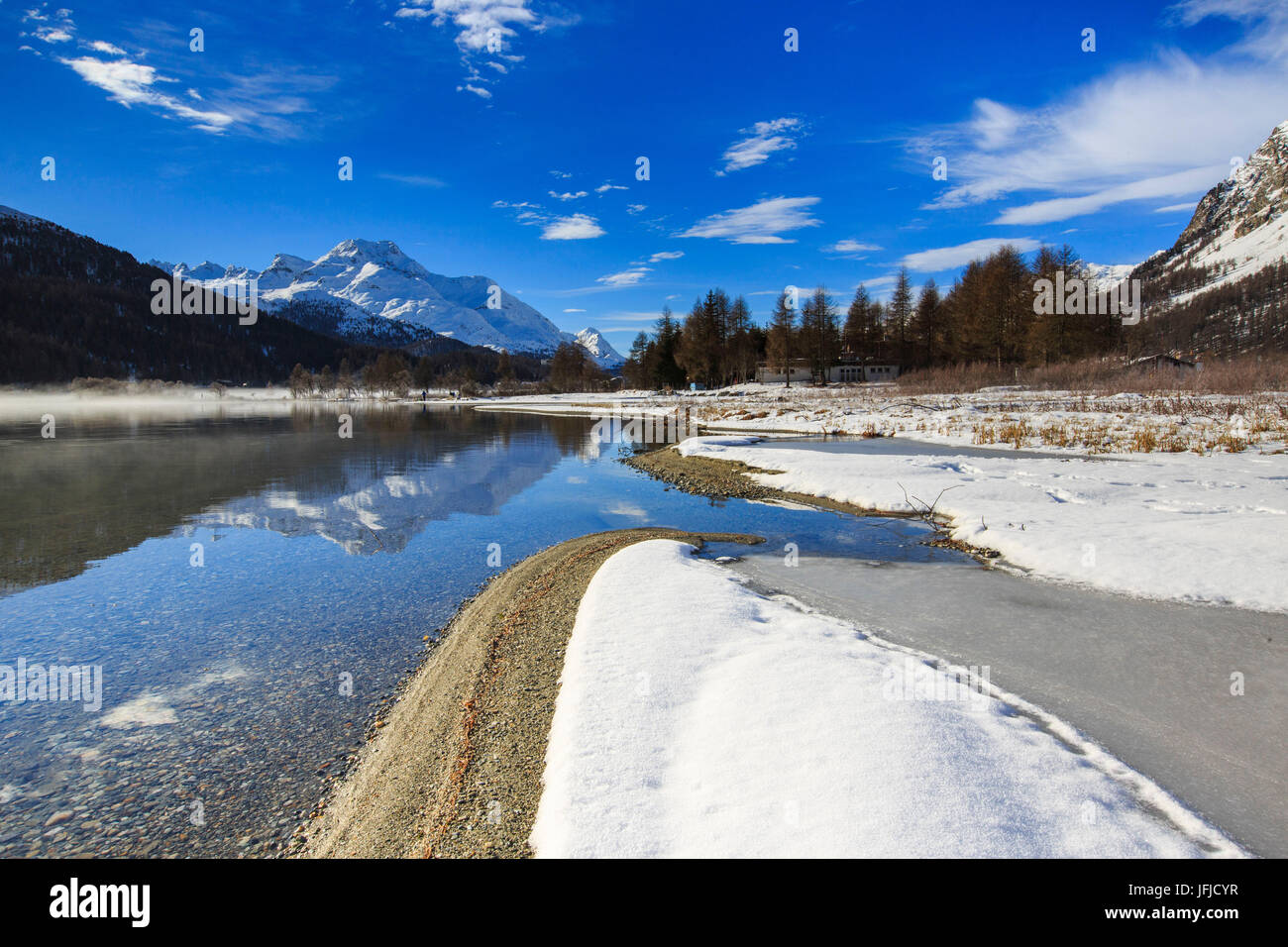 Vette innevate sono riflesse nel lago di Silvaplana ancora parzialmente congelato Maloja Cantone dei Grigioni Engadina Svizzera Europa Foto Stock