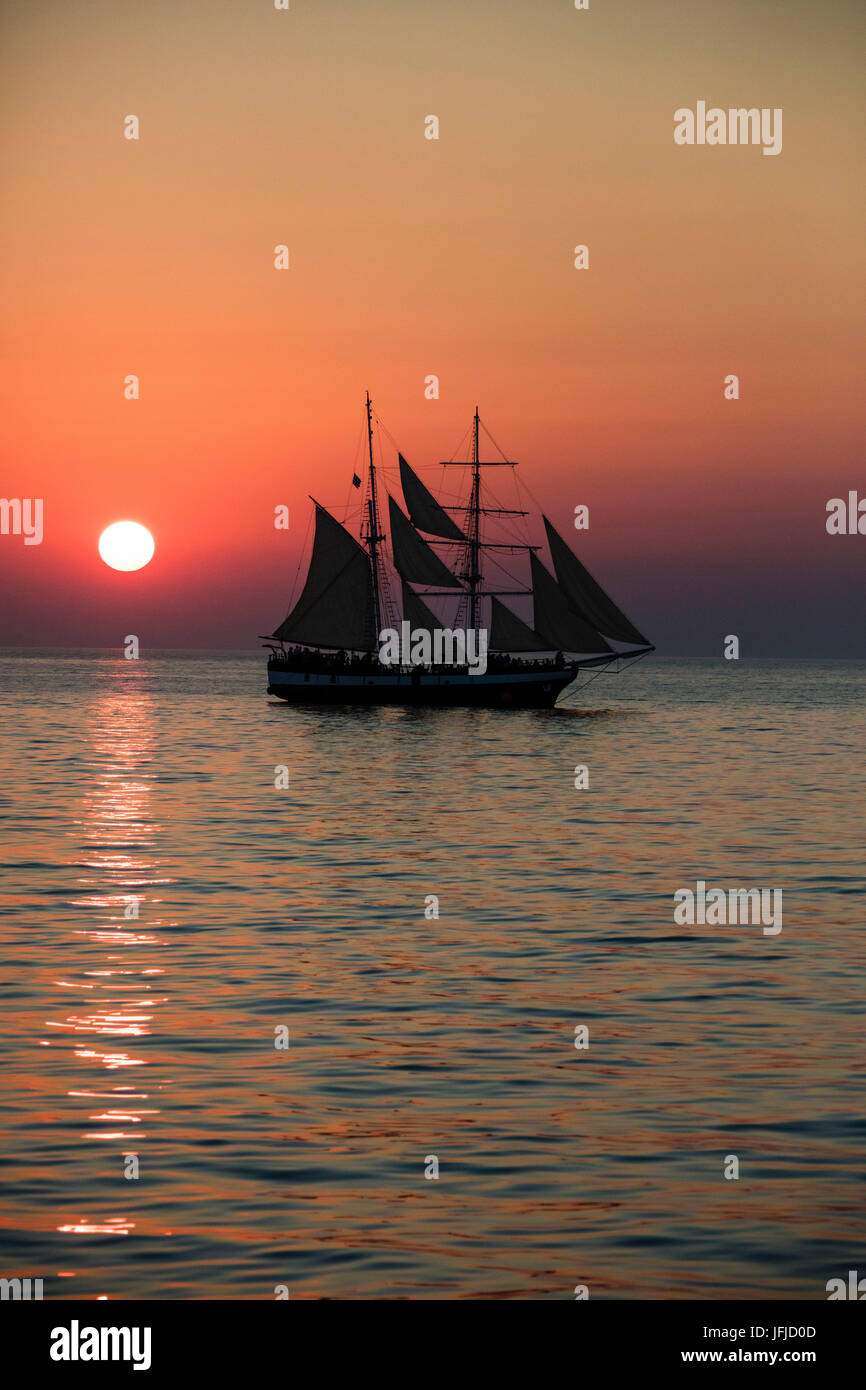 Un veliero nel Mare Egeo mentre il sole tramonta Santorini Cyclades Grecia Europa Foto Stock