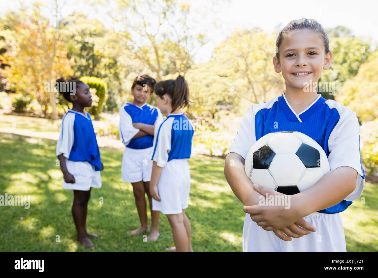 Ragazza in posa con la sua squadra di calcio in background Foto Stock