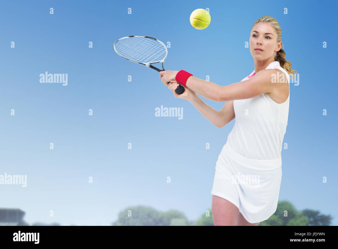 Atleta giocando a tennis con un racket contro la vista di un campo da gioco contro il cielo blu Foto Stock