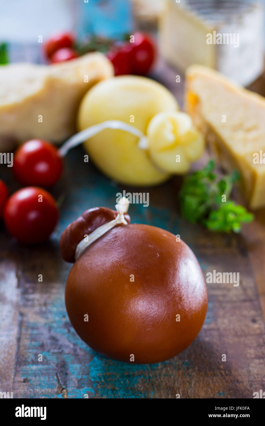 Tradizionale formaggio duro italiano Provolone Caciocavallo affumicato e bianco su sfondo di legno Foto Stock