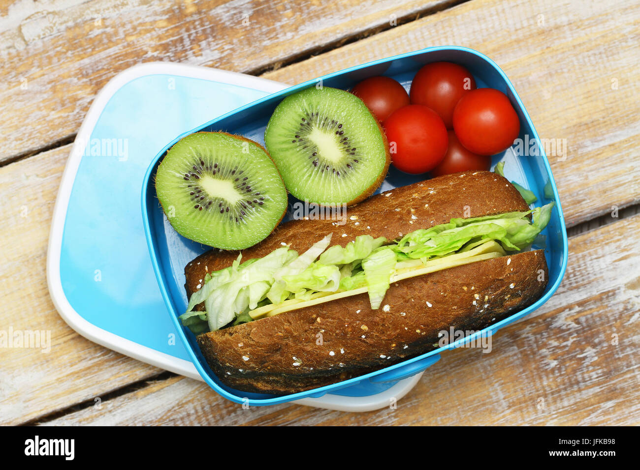 Un sano pranzo al sacco contenente formaggio marrone sandwich, pomodori ciliegini, kiwi Foto Stock