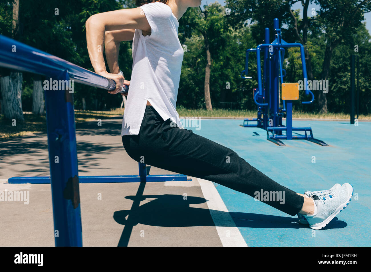 Close-up di una giovane donna di atletica a fare gli esercizi per i tricipiti sul parco giochi d'estate. Concetto di uno stile di vita sano. Foto Stock