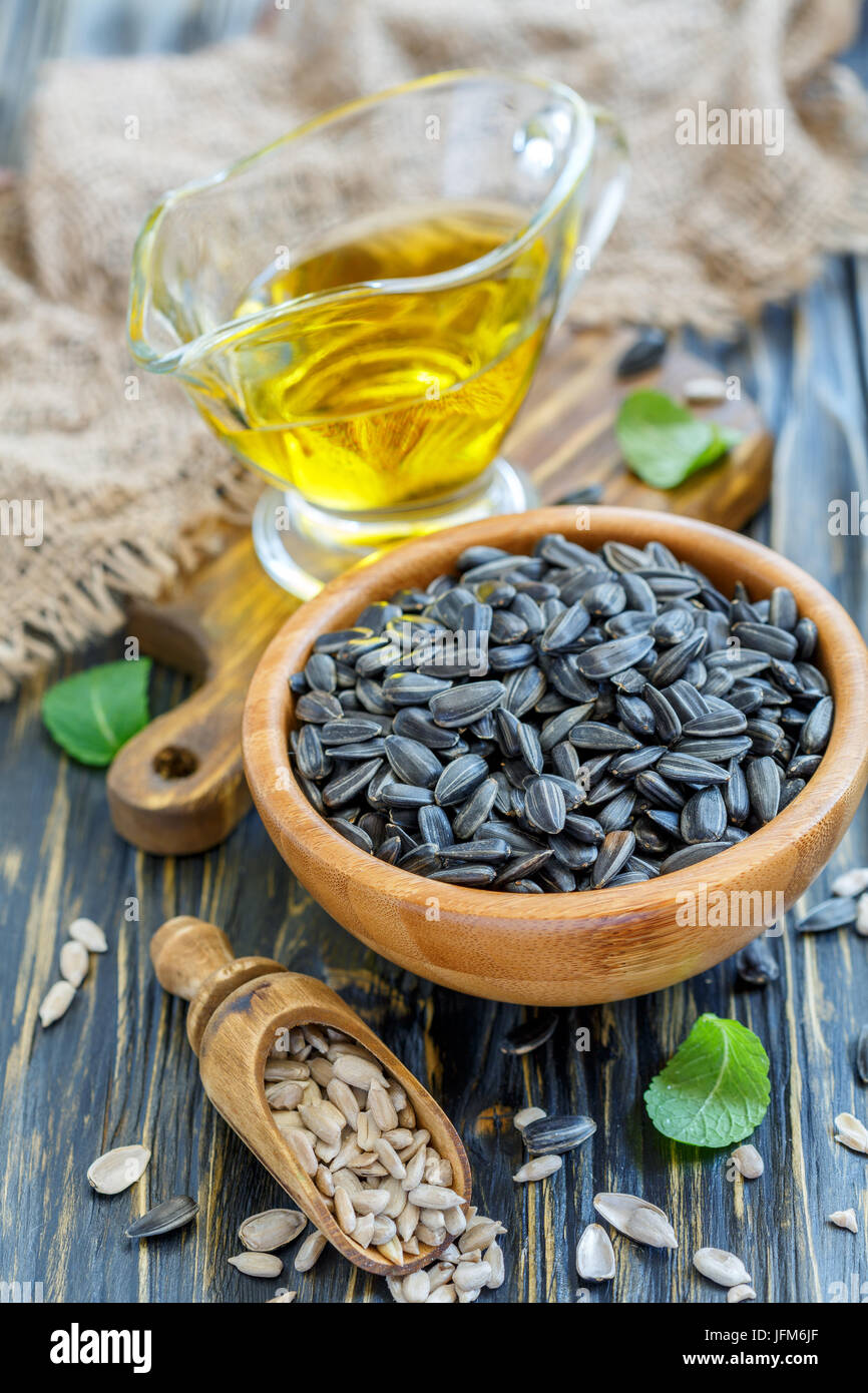 Ciotola di semi di girasole e una tazza di olio di semi di girasole. Foto Stock