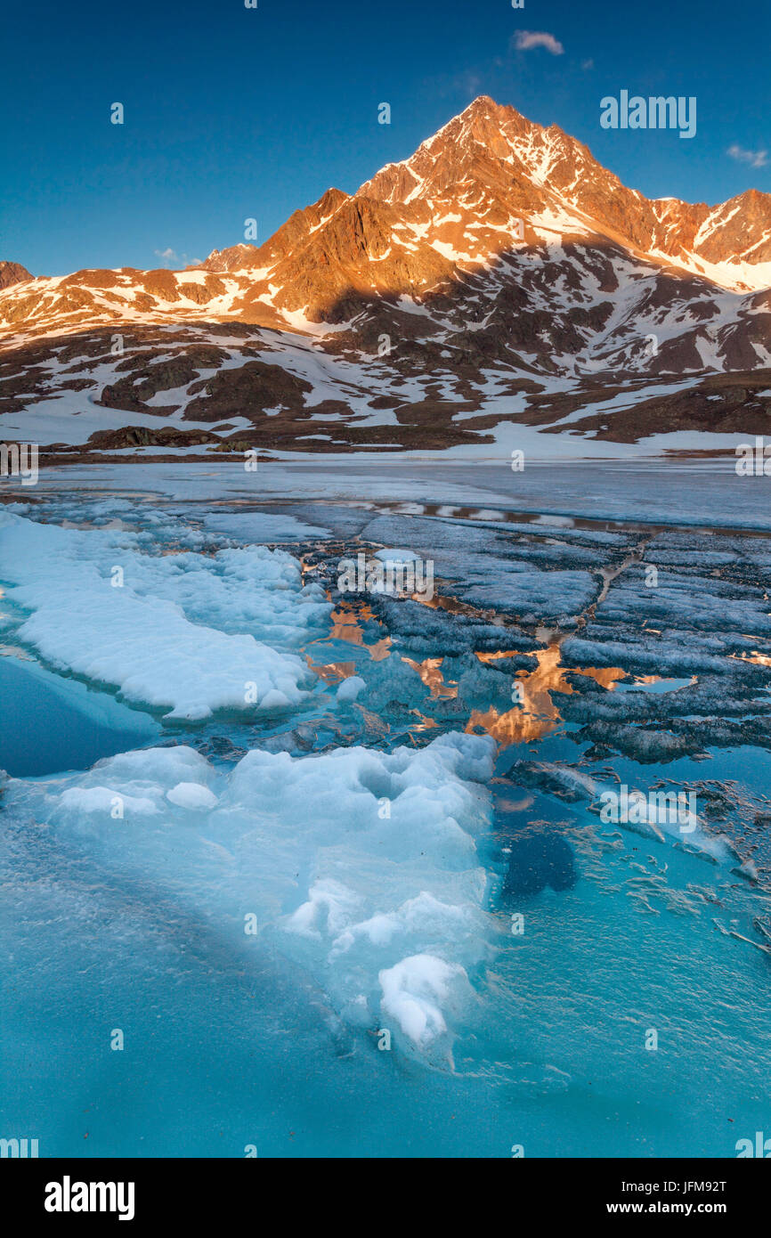 Passo Gavia, Parco Nazionale dello Stelvio, provincia di Sondrio, Lombardia, Italia, Tre Signori picco è riflessa al lago bianco al tramonto Foto Stock