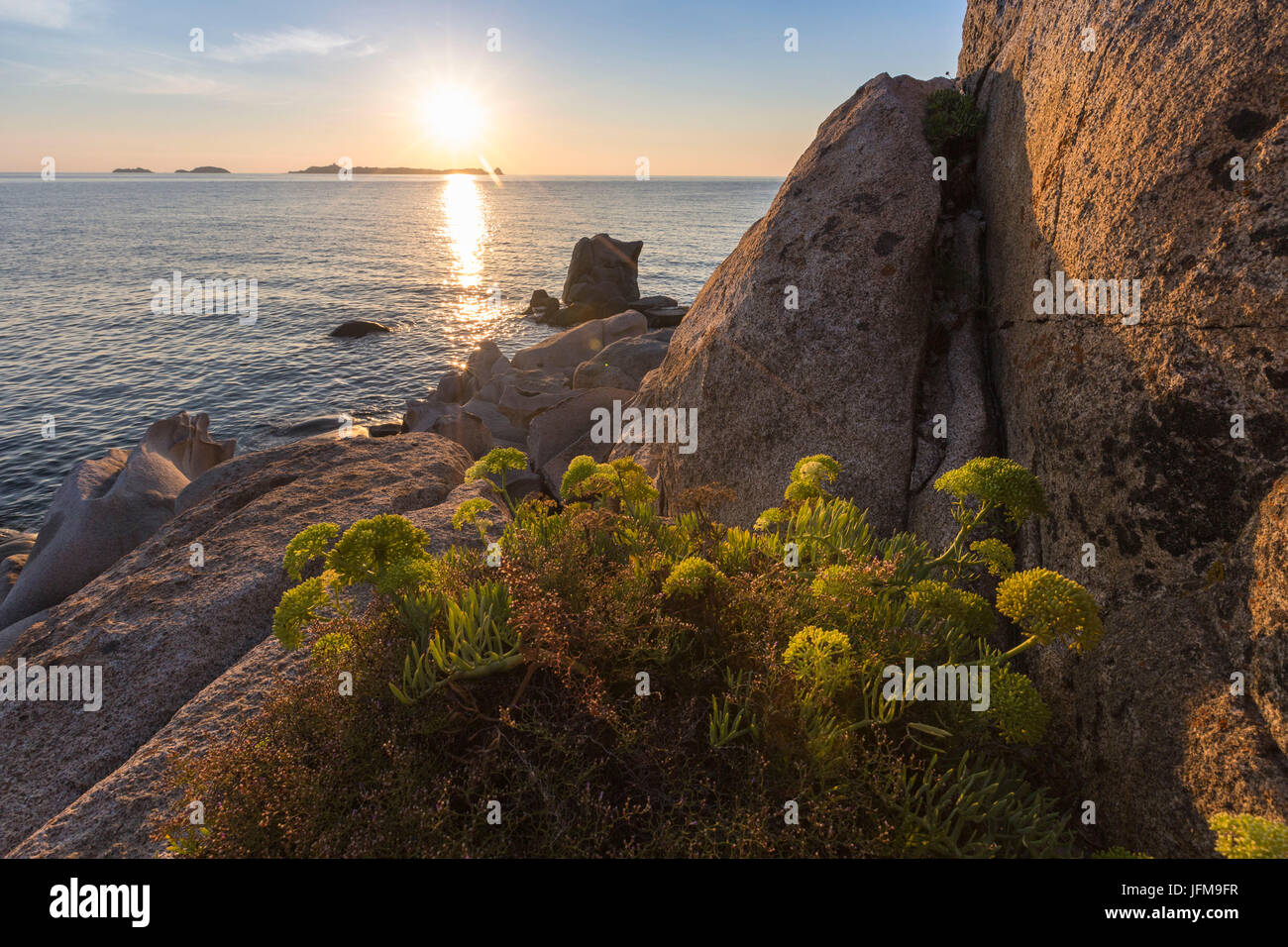 Raggi di sole si riflettono sul mare azzurro incorniciato da rocce e vegetazione Punta Molentis Villasimius Cagliari Sardegna Italia Europa Foto Stock
