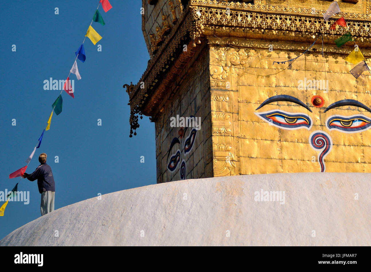 Un sistema uomo bandiere delle preghiere su lo stupa di Swayambhunath a Kathmandu in Nepal Foto Stock