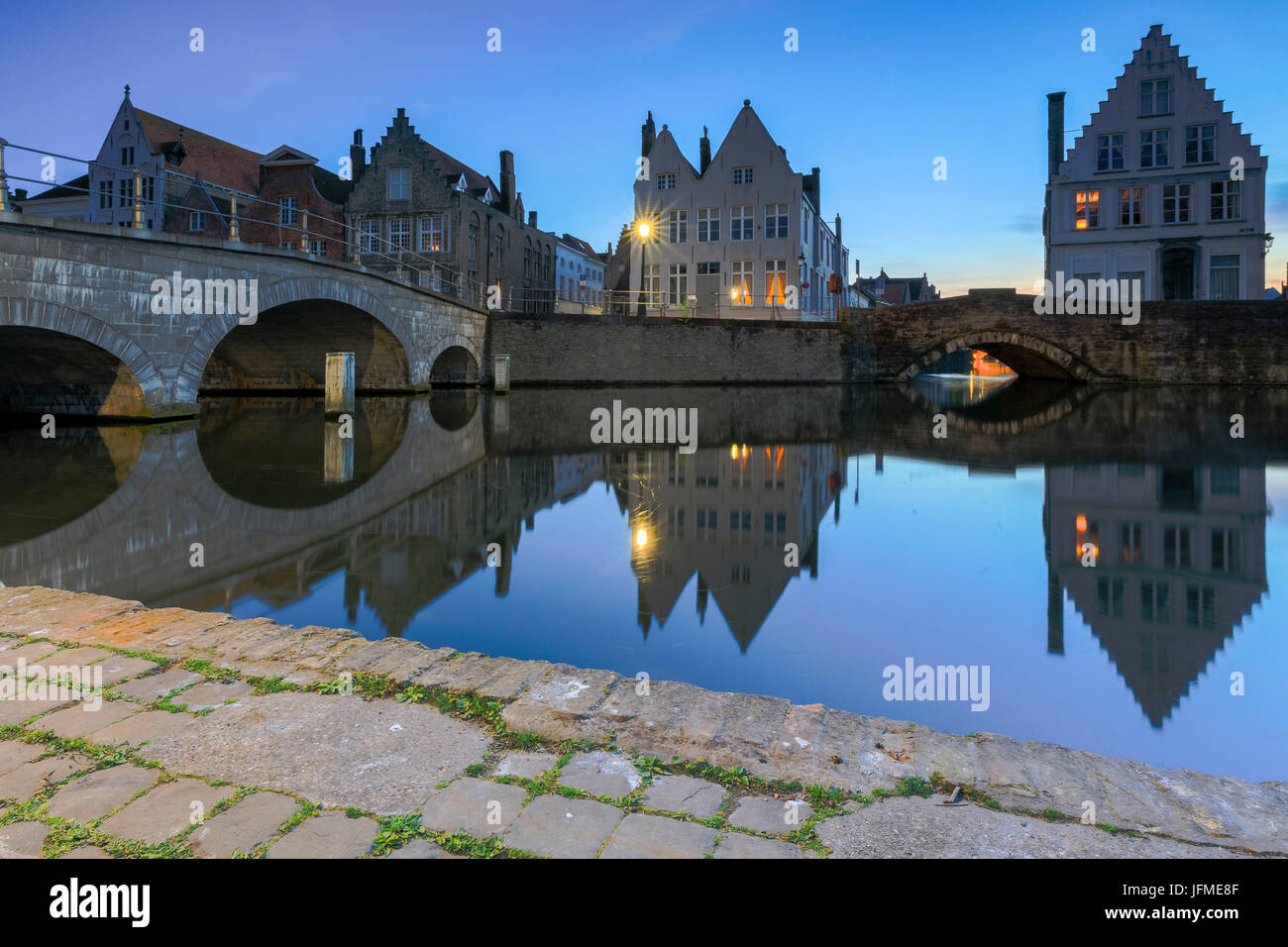 Le luci del tramonto su edifici storici del centro città si riflette nei tipici canali di Bruges Fiandre Ovest Europa Belgio Foto Stock