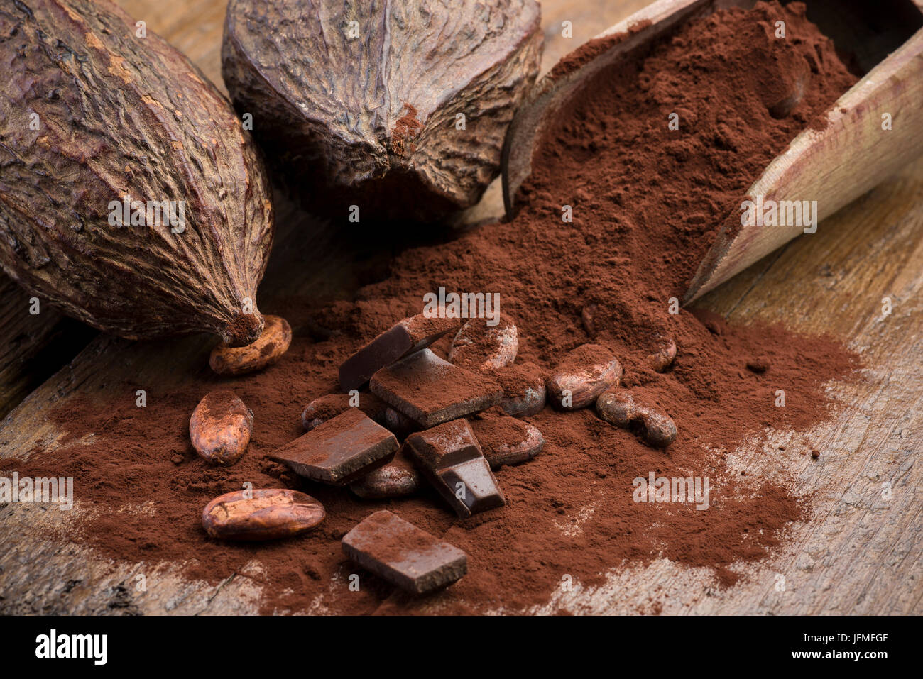 Baccelli di cacao con le fave di cacao, la polvere di cacao e cioccolato di blocco sul tavolo di legno Foto Stock