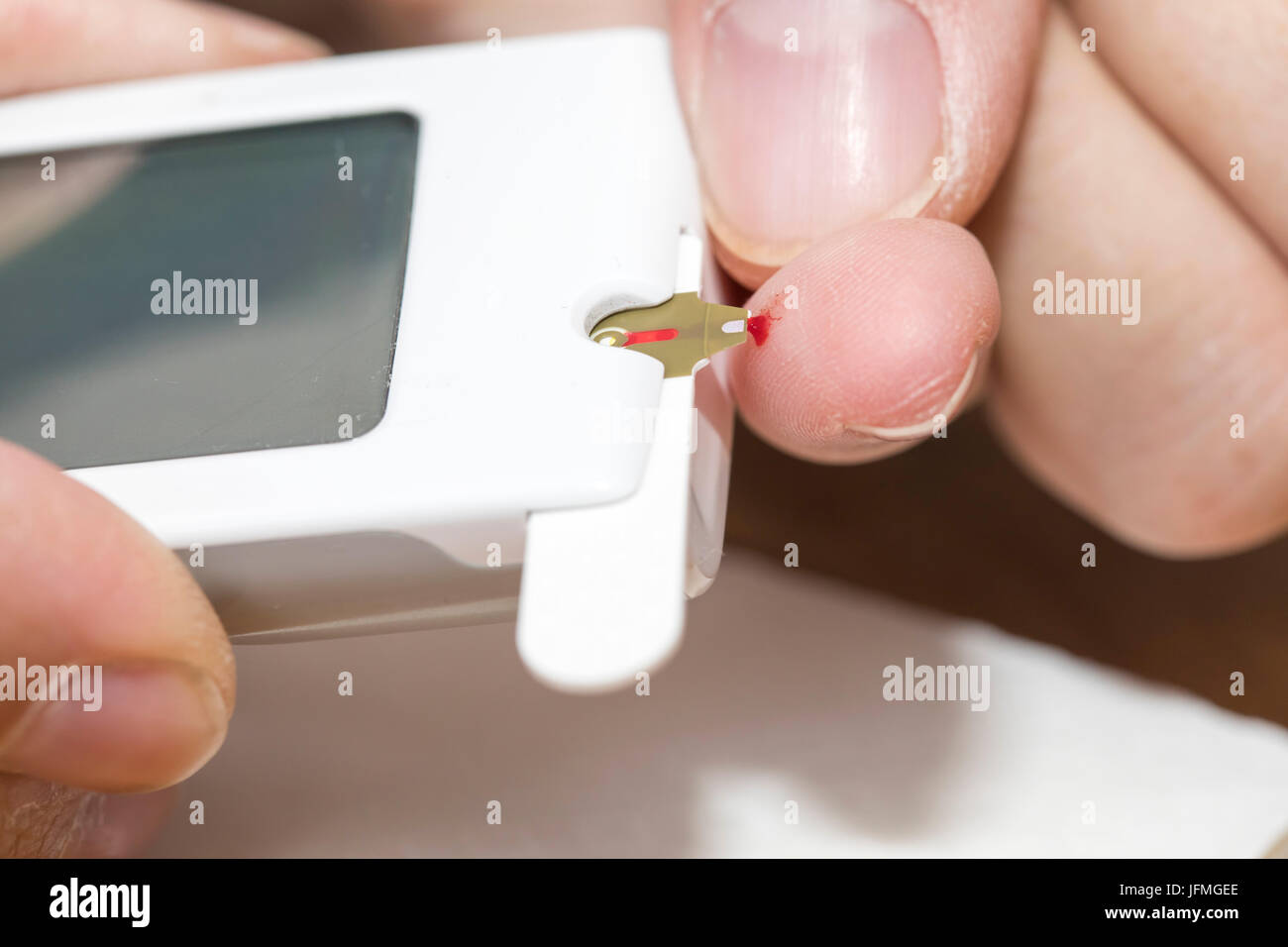 I diabetici con un livello di glucosio nel sangue il test con un dispositivo a lancia una goccia di sangue viene generato in corrispondenza del fingertip, per il livello di zucchero nel sangue di misurazione, Foto Stock