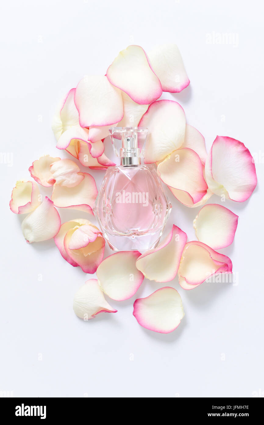 Bottiglia di profumo con petali di fiori su sfondo chiaro. Profumeria, di raccolta della fragranza. Accessori per le donne. Foto Stock