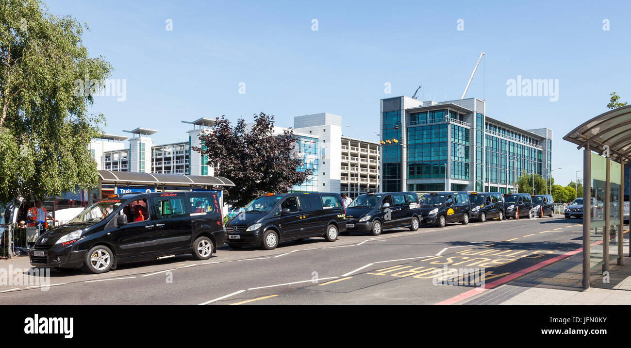 Taxi con taxi schierate in Comet Road, Birmingham Airport, West Midlands, England Regno Unito. Parcheggio multipiano e Diamond House in background. Foto Stock