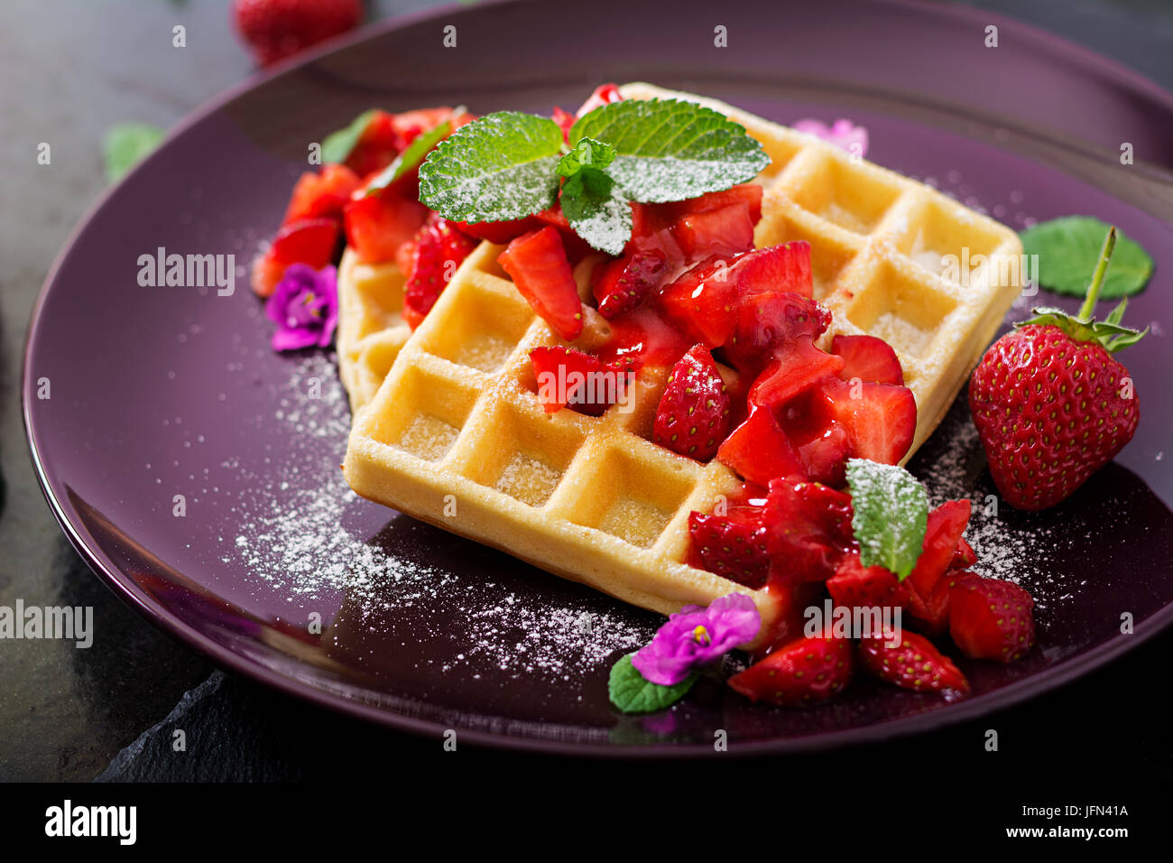 Belgio di wafer con fragole e sciroppo su una piastra. Foto Stock