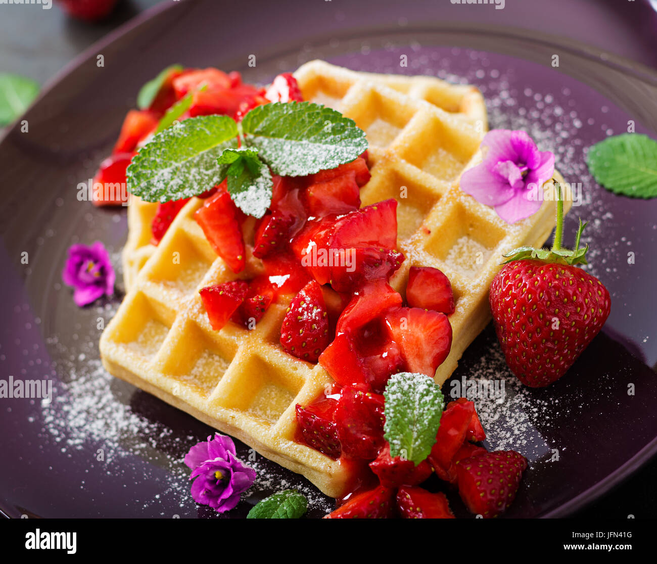 Belgio di wafer con fragole e sciroppo su una piastra. Foto Stock