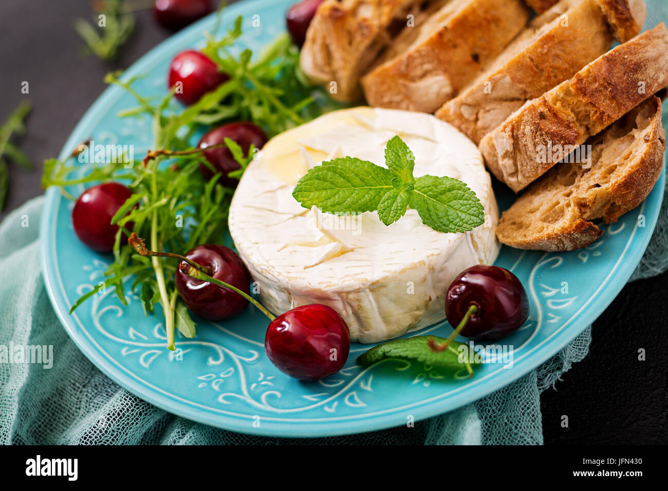 Cotta formaggio Camembert, toast e insalata di rucola con ciliegie dolci. Foto Stock