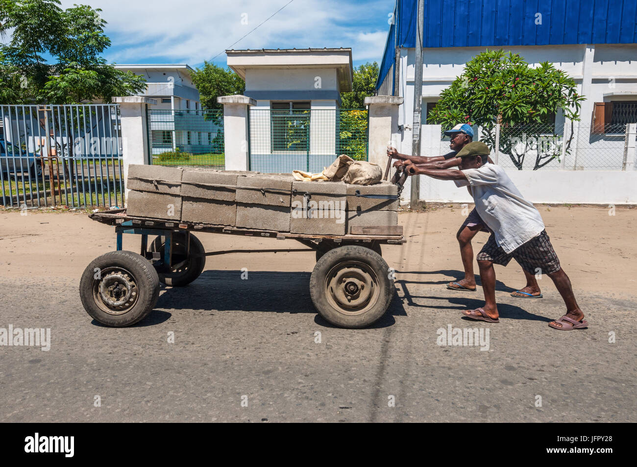 Toamasina, Madagascar - Dicembre 22, 2017: Unidentified Madagascar uomini spingere enorme carro con i mattoni a Toamasina (Tamatave), Madagascar, Africa orientale Foto Stock