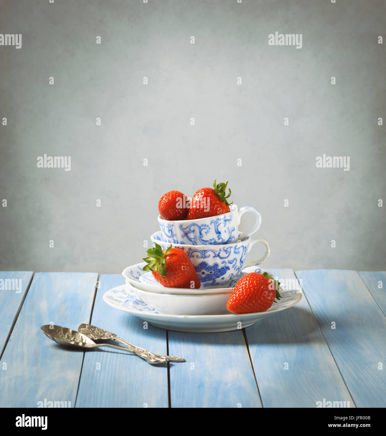 Fragole in coppe di vintage e piattini sul tavolo rustico Foto Stock