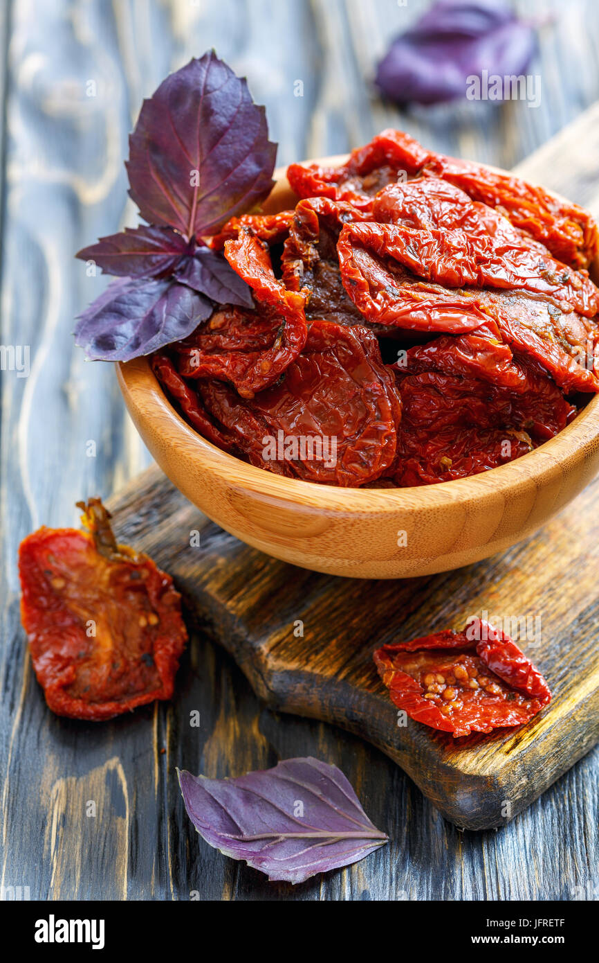 Pomodori secchi e basilico rosso in una ciotola di legno. Foto Stock