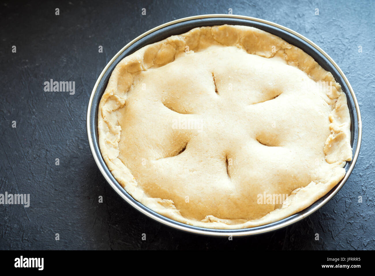 La cottura di una torta. Crudi torta di pasta frolla (pasta, riempimento) in una teglia, la preparazione per la cottura. Torta di greggio, pronto per cuocere al forno, il processo di cottura. Foto Stock