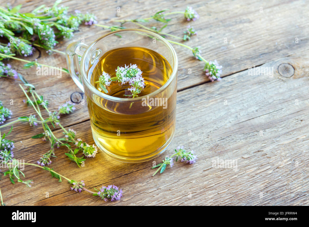 Salutare tè alle erbe con mazzetto di fresco timo selvatico e vintage tè-filtro sul vecchio sfondo di legno. Tazza di tè di timo, la bevanda a base di erbe. Foto Stock