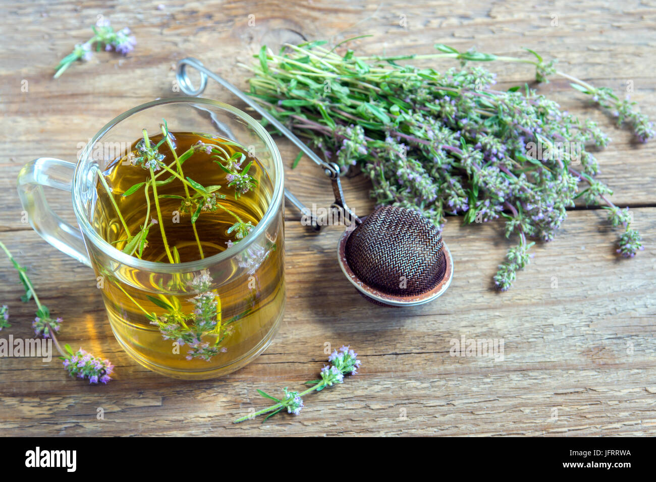 Salutare tè alle erbe con mazzetto di fresco timo selvatico e vintage tè-filtro sul vecchio sfondo di legno. Tazza di tè di timo, la bevanda a base di erbe. Foto Stock