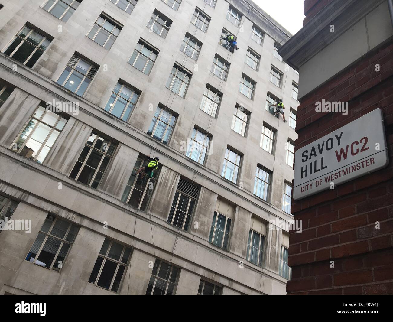 Elevato aumento detergenti per finestre sono al lavoro su un edificio nel centro di Londra dal Savoy Hill Street in WC2. Foto Stock