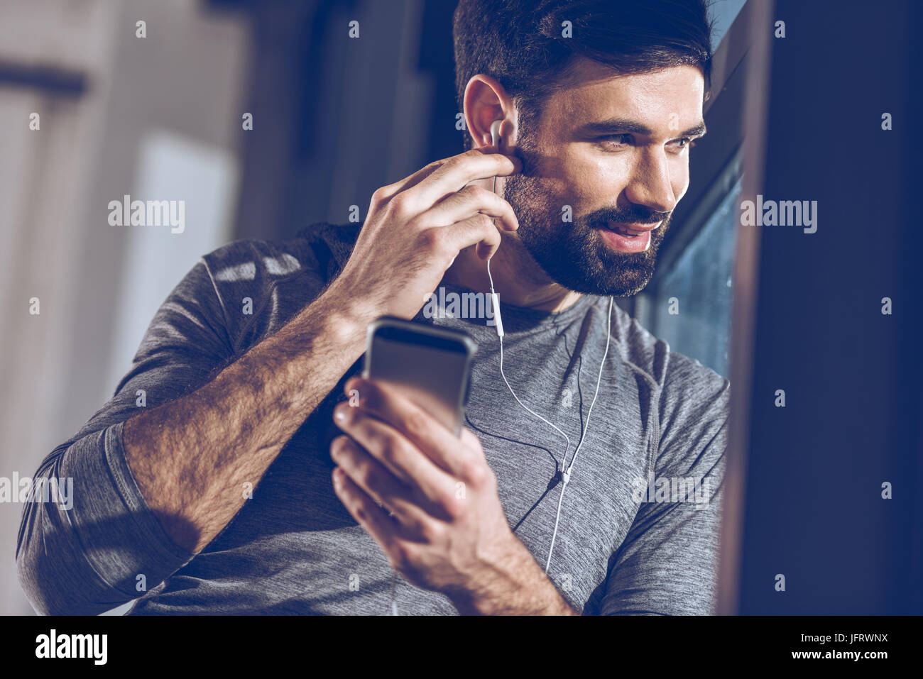 Ritratto di uomo che ascolta la musica in cuffia e guardare dalla finestra Foto Stock