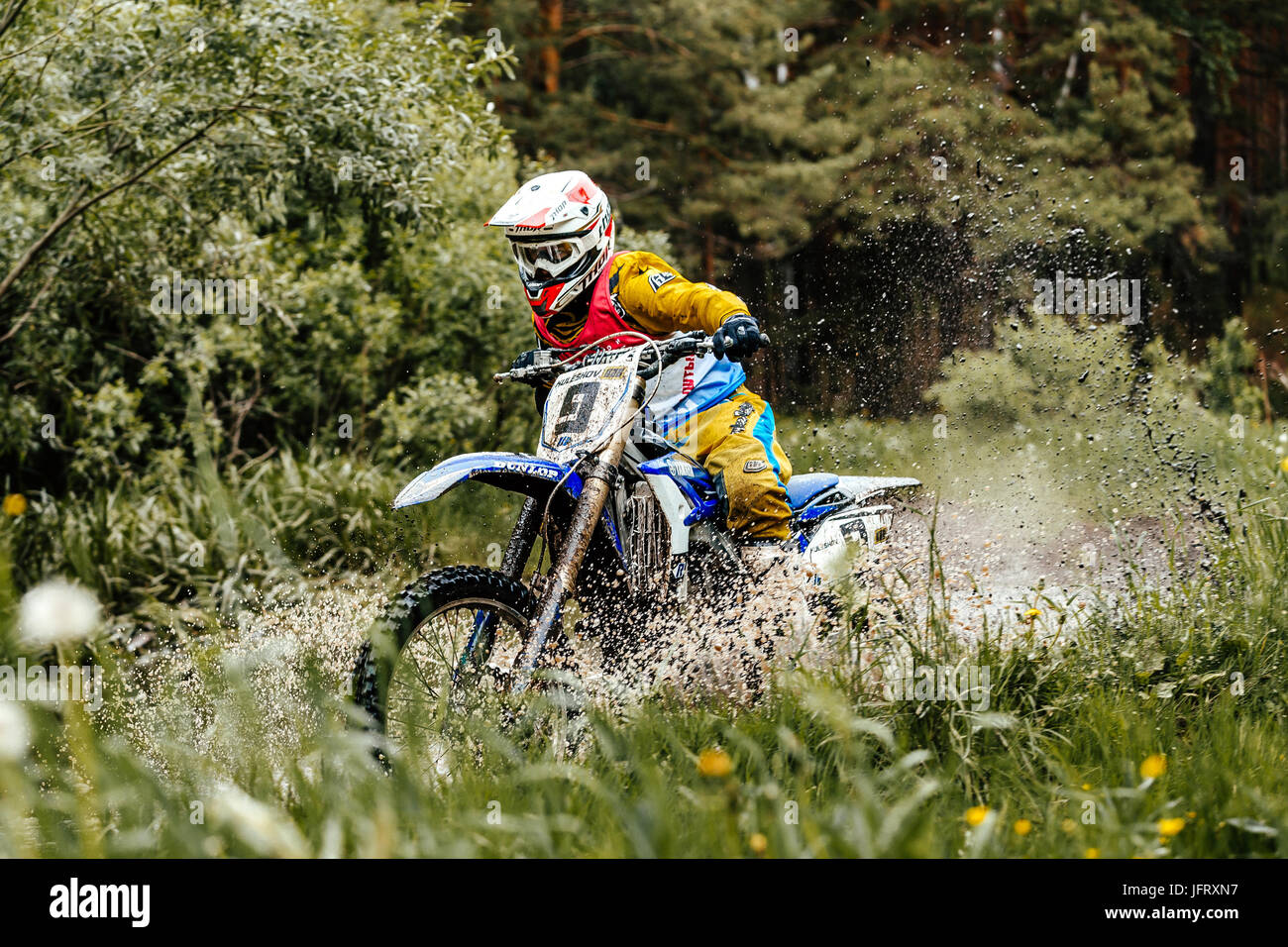 Motociclo attraversa pozzanghere di acqua e fango in foresta durante l'Ural Cup di Enduro Foto Stock