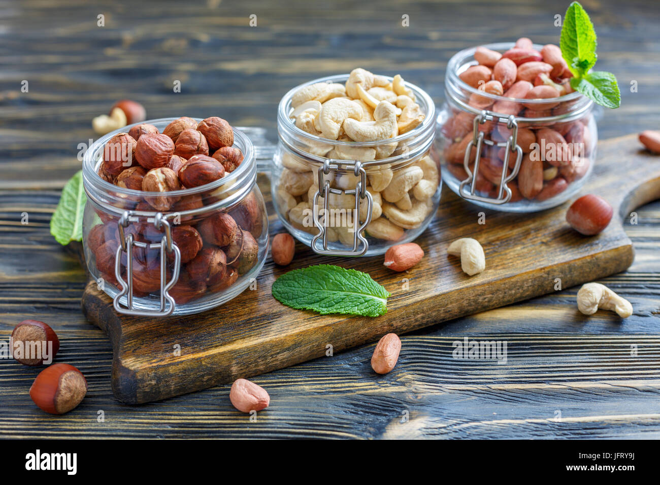 Vasi di vetro con nocciole, anacardi e arachidi. Foto Stock