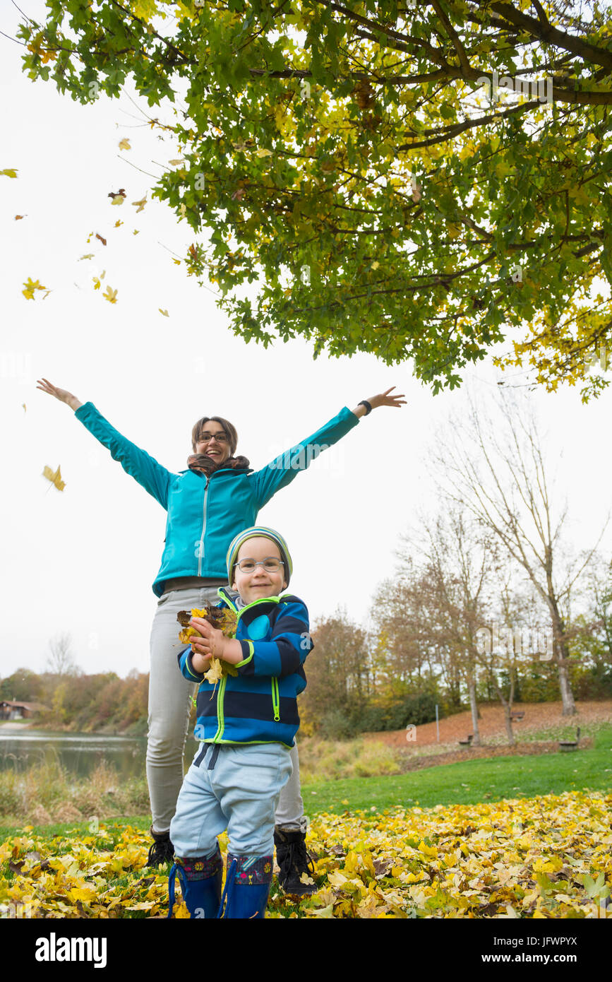 Madre e figlio godendo lanciando Foglie di autunno in aria Foto Stock