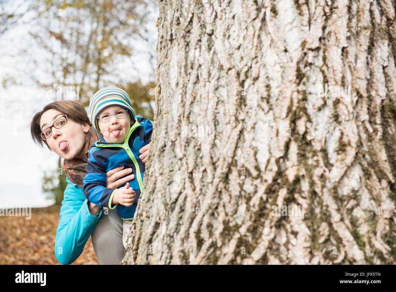 Madre e figlio spuntavano erede saloni affacciati alle spalle del grande albero in autunno scenario Foto Stock