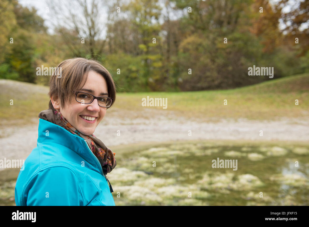 Donna sorridente in piedi alla riva del lago Foto Stock