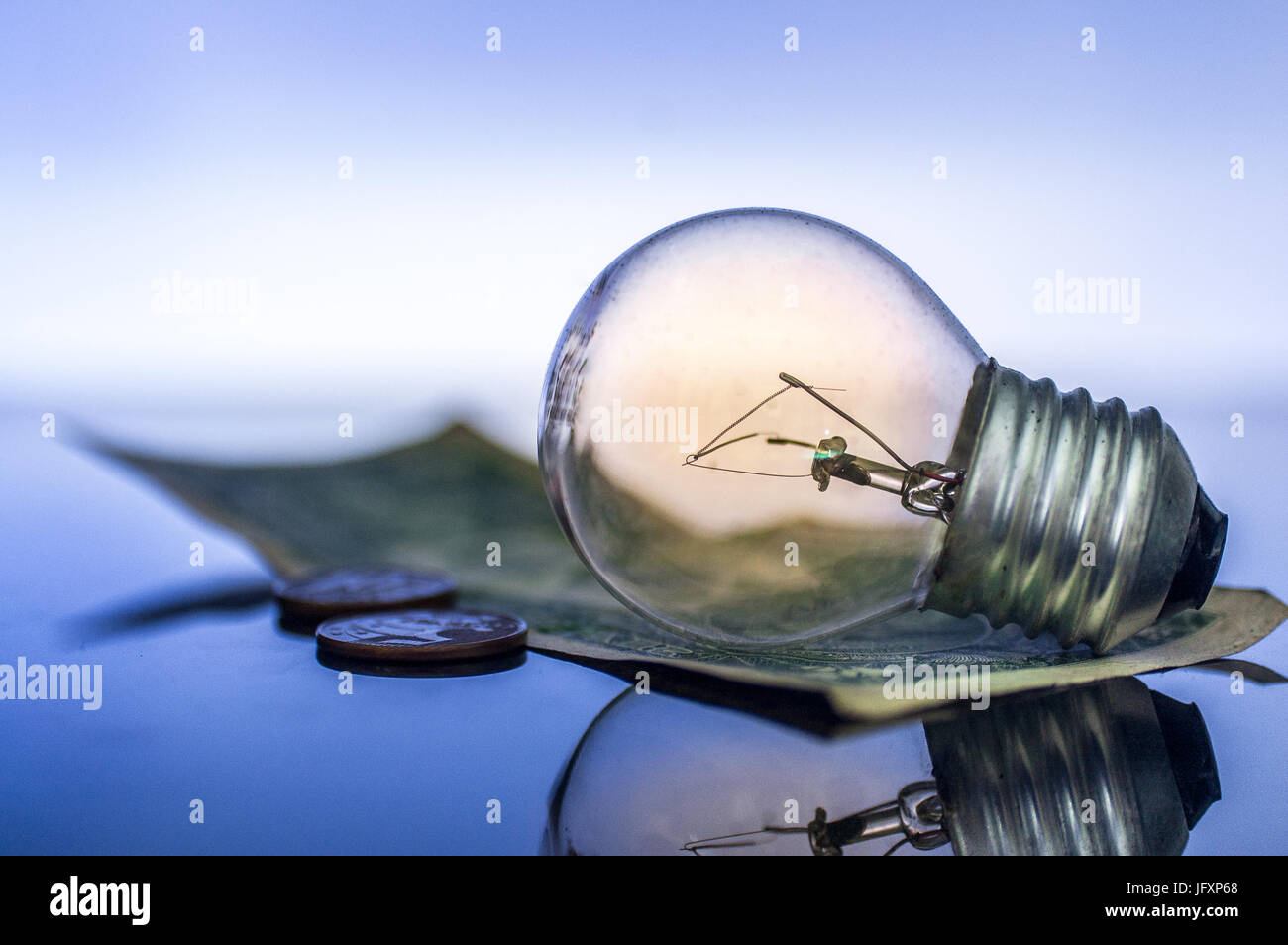 Lampadina della luce, con noi / USA Dollaro e monete, riflettendo sul tavolo di vetro. Denaro e finanze, risparmio e business idea concetto. Foto Stock