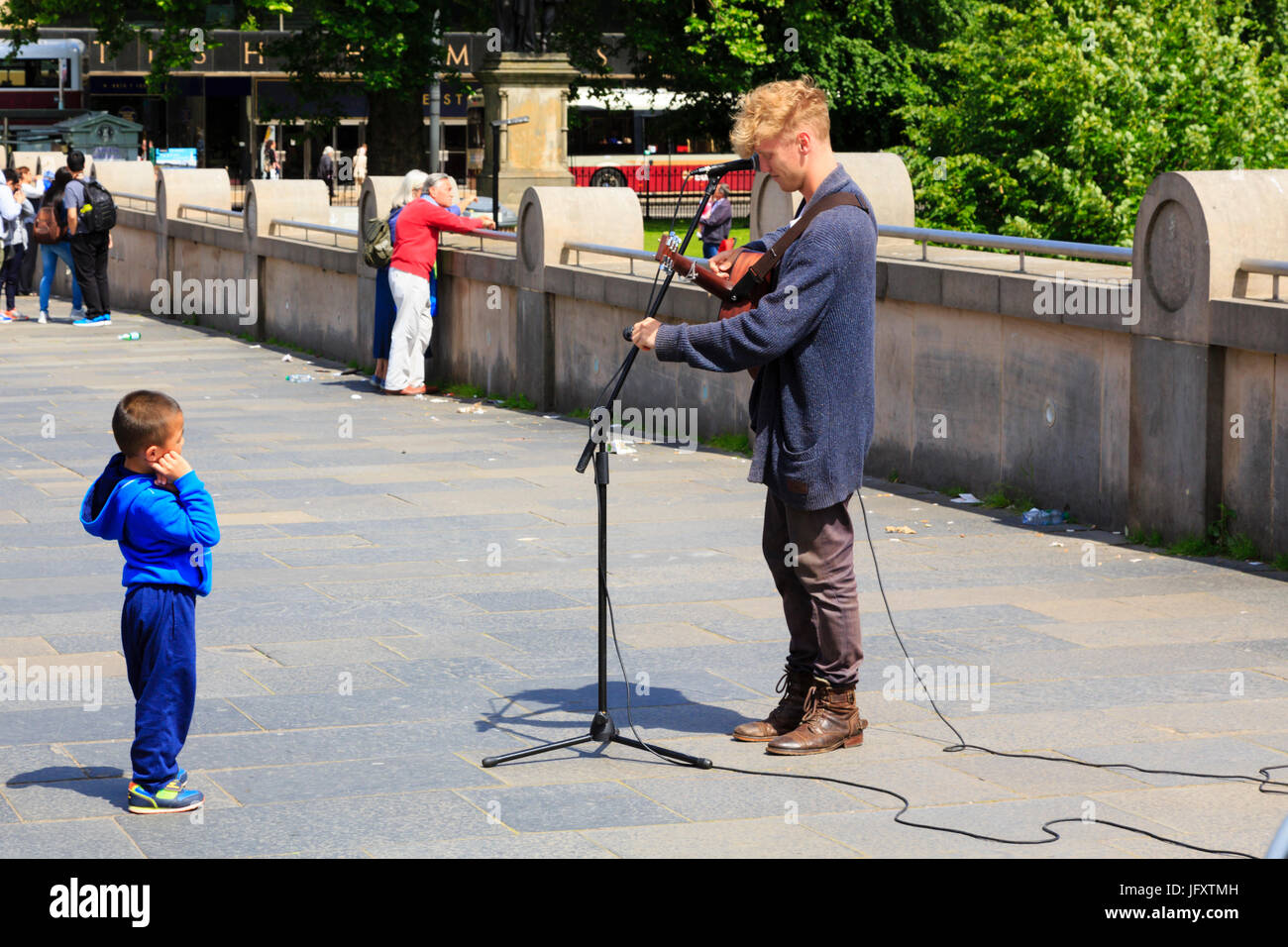 Busker con il piccolo bambino guardando al di fuori della Scottish National Gallery, Edimburgo, Scozia. Foto Stock