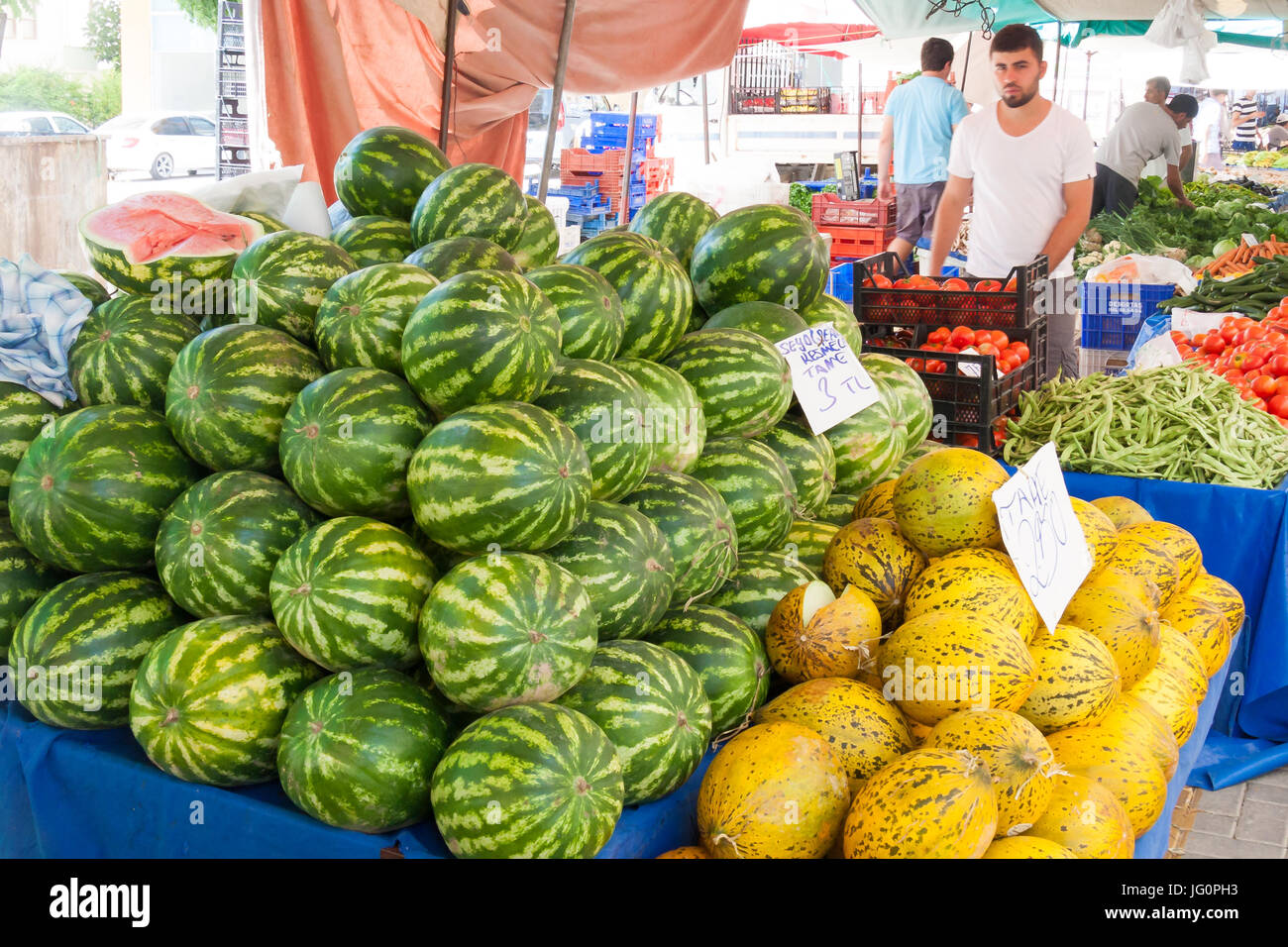 Un uomo attende i clienti sul suo mercato bancarella vendendo i meloni e verdure, Alanya, Turchia Foto Stock