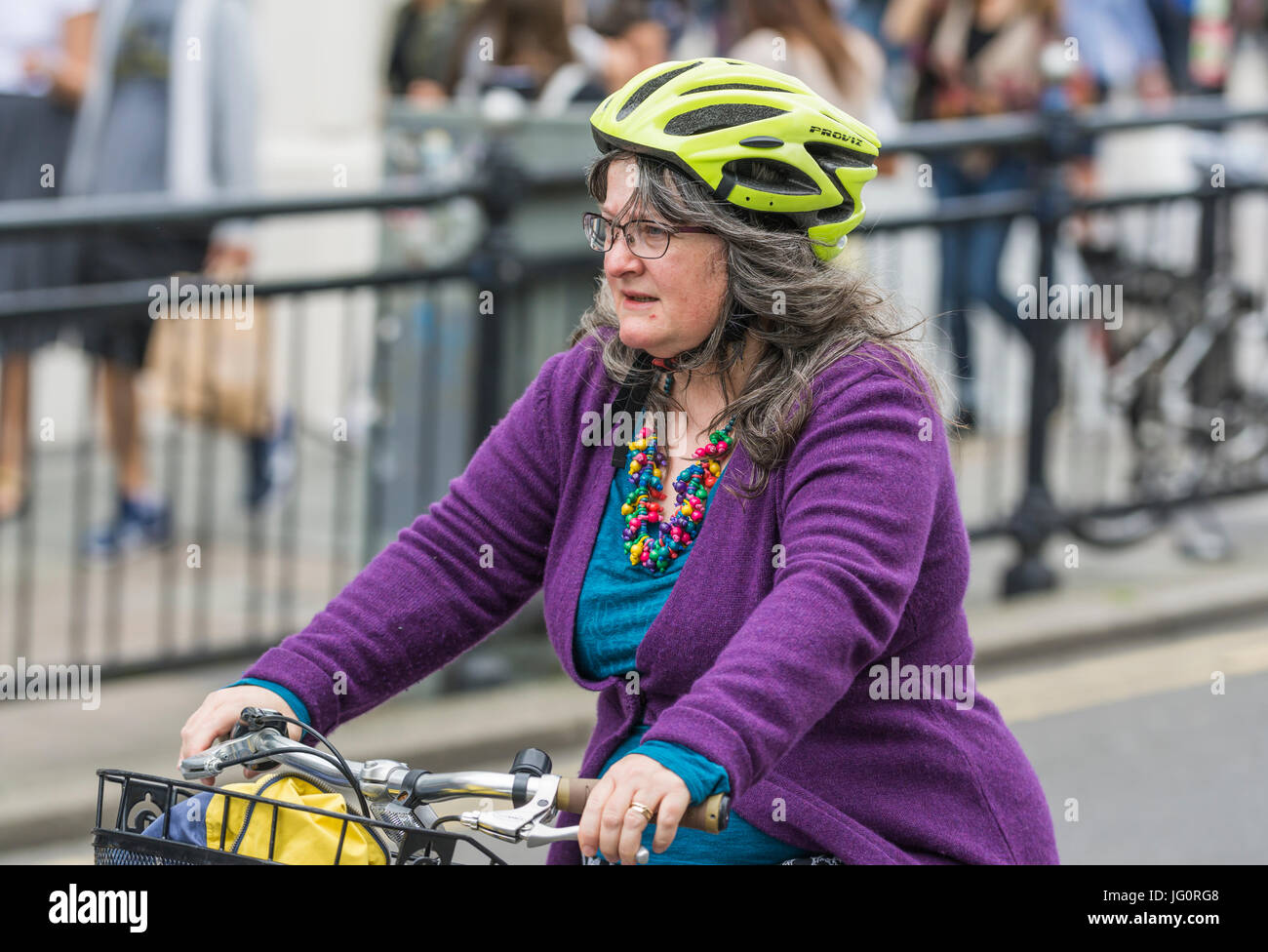 Di mezza età ciclista femmina di una bicicletta mentre indossa un casco in una città. Foto Stock
