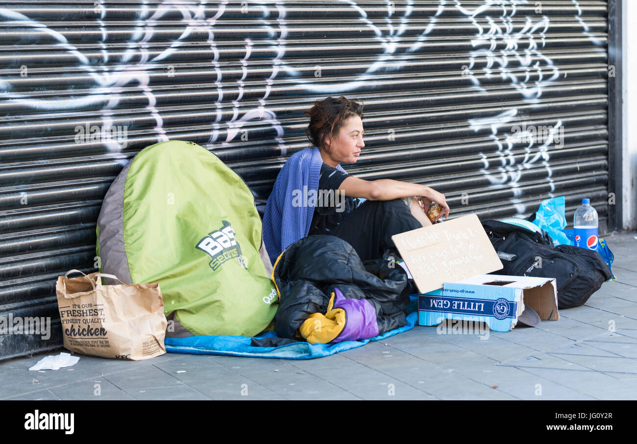 Senzatetto donna seduta al di fuori delle strade in Brighton, East Sussex, Inghilterra, Regno Unito. Foto Stock