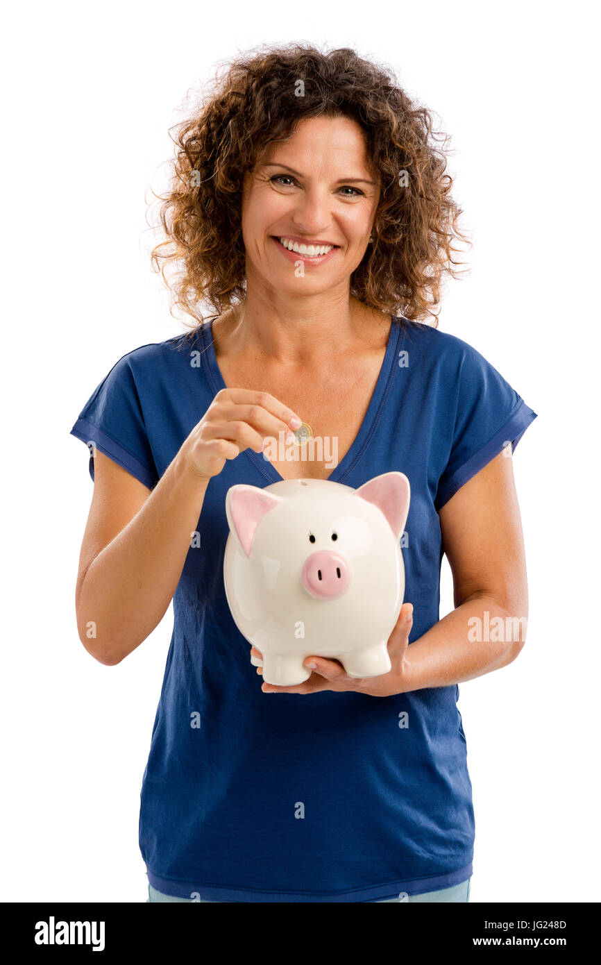 Ritratto di un felice donna di mezza età messa un po' di soldi su un Piggybank Foto Stock