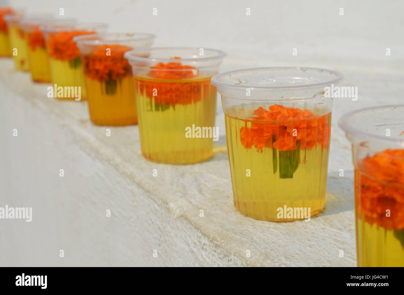 Bicchieri con acqua e fiori di garofano al grande stupa Bodnath a Kathmandu, Nepal. Foto Stock