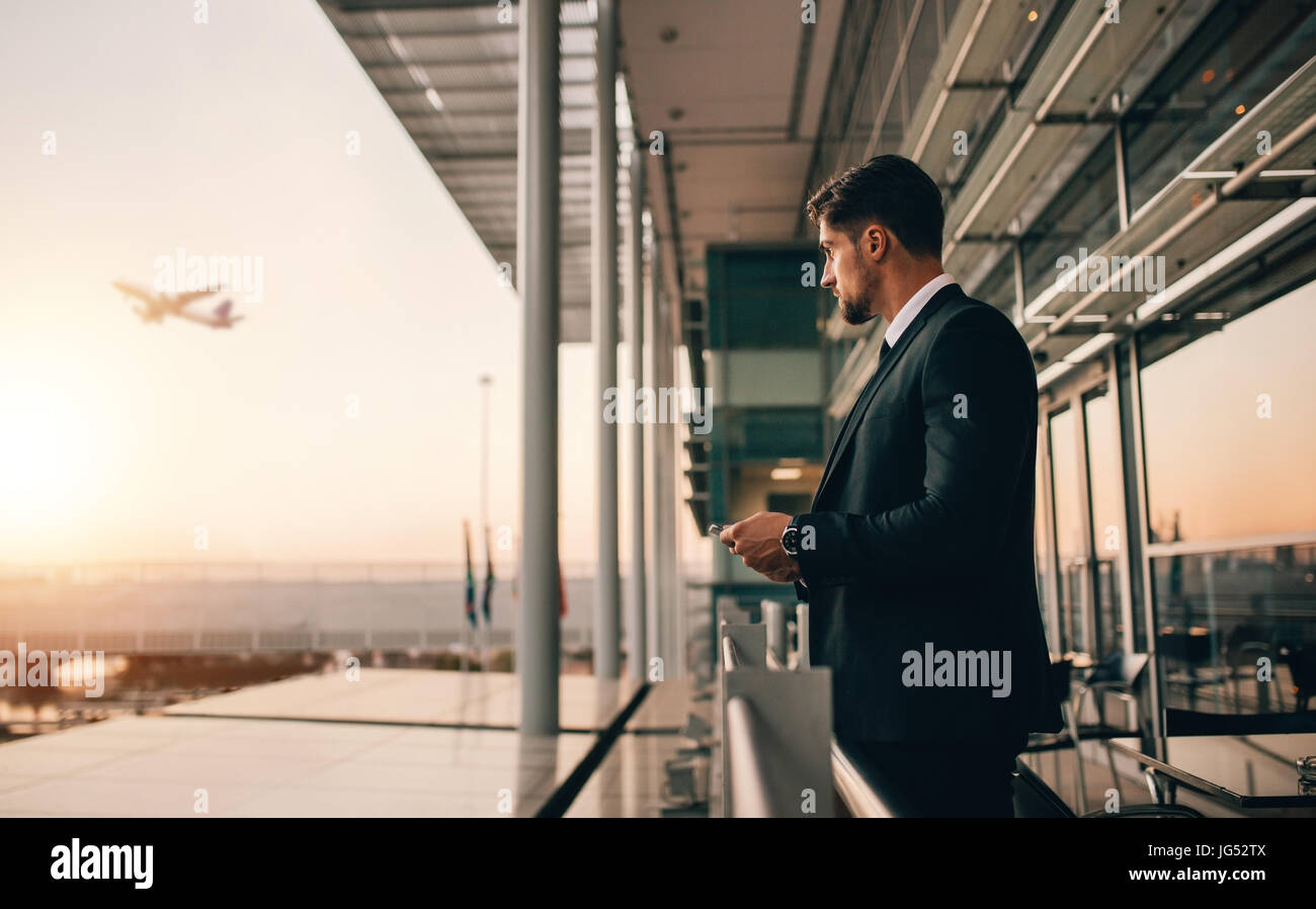 Airport Lounge balcone e guardando aereo decollare. Business man in attesa per il suo volo. Foto Stock