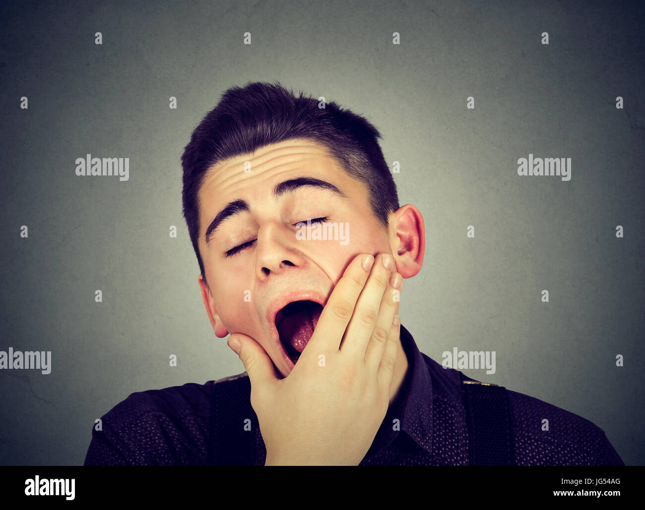 L'uomo sbadigliare isolato su sfondo grigio Foto Stock