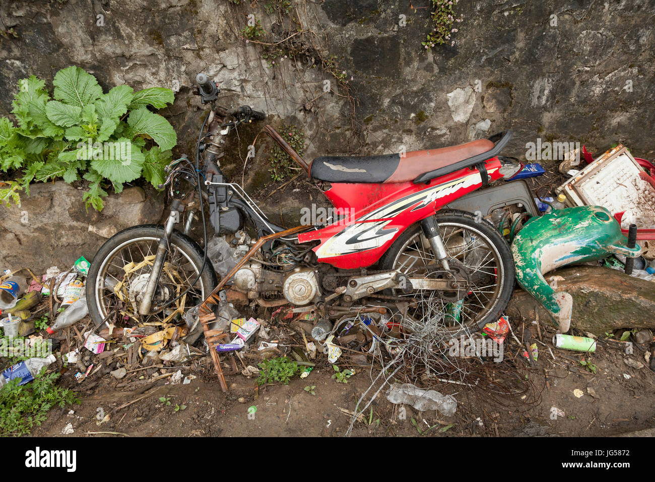 Spazzatura compresa una vecchia moto gettati in un fosso sul ciglio della strada, Vietnam. Foto Stock