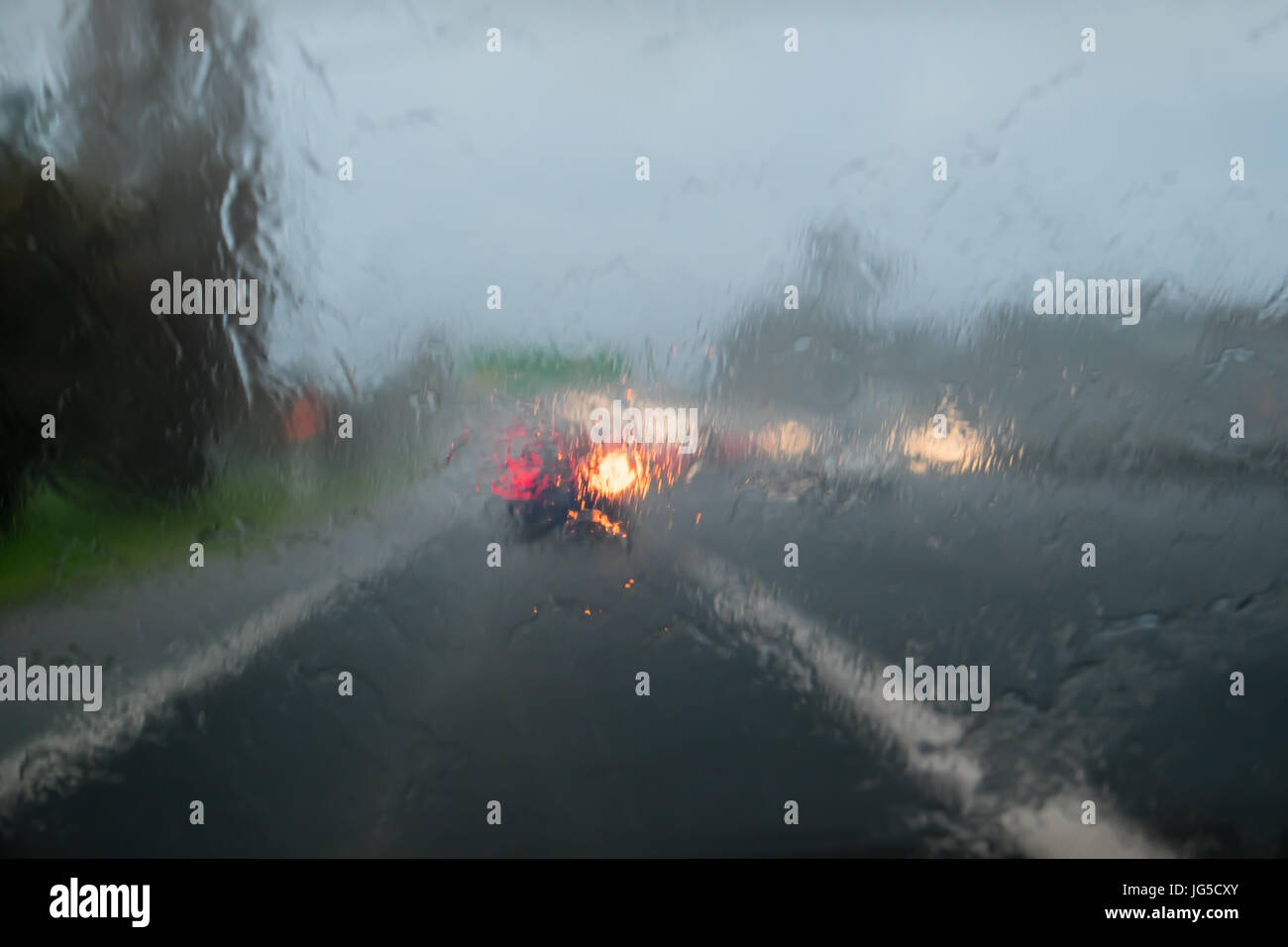 La guida con pioggia sul parabrezza auto sulla Statale 1, Auckland, Nuova Zelanda, NZ - auto davanti indica Foto Stock