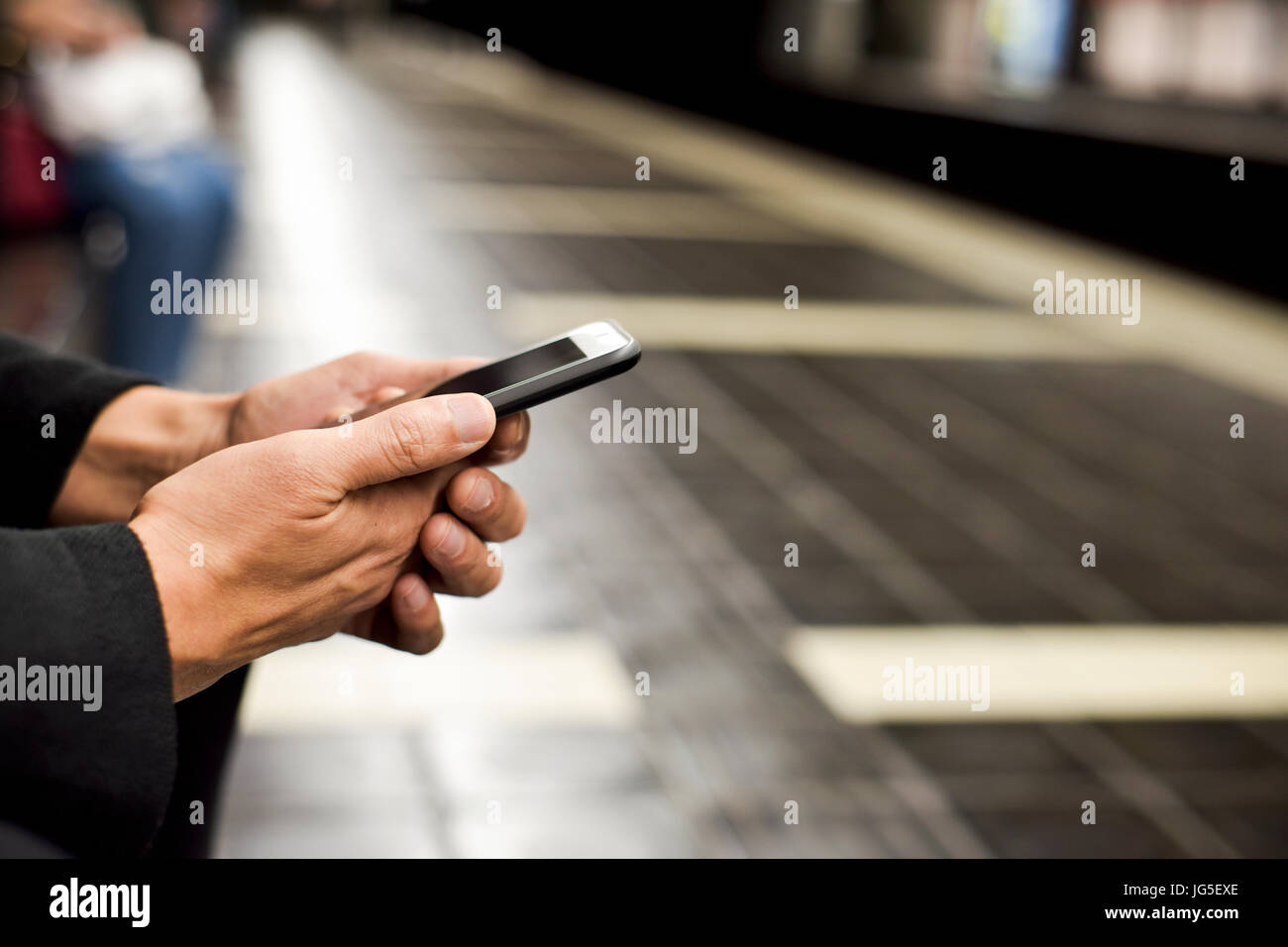 Primo piano di un giovane uomo caucasico utilizzando uno smartphone in un treno della metropolitana o tram station Foto Stock